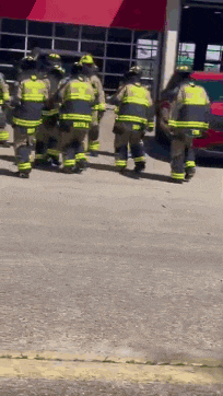 a group of firefighters are walking down the street .