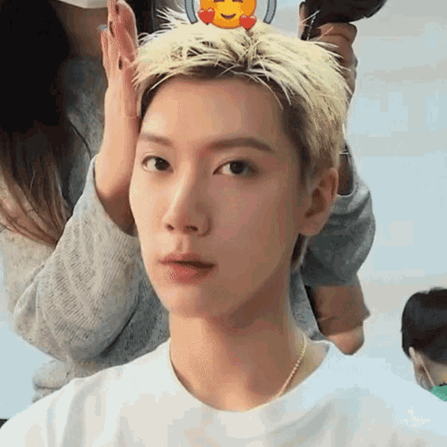 a young man with blonde hair is getting his hair blow dried by a hairdresser .