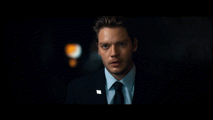 a man in a suit and tie is standing in the dark