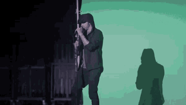 a man is singing into a microphone while standing on a pole