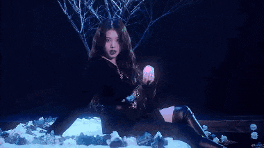 a woman is sitting in the snow holding a glowing ball in her hands .