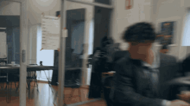 a blurred image of a man in a suit walking through a doorway