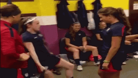a group of female athletes are standing in a locker room