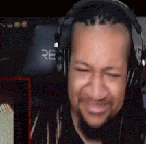 a man with dreadlocks wearing headphones is making a funny face .