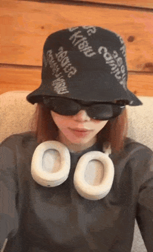 a woman wearing a bucket hat and headphones is taking a picture