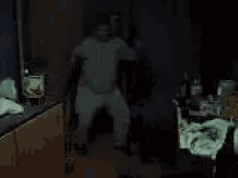 a man is dancing in a dark room with his arms in the air