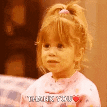 a little girl is saying thank you with a heart .