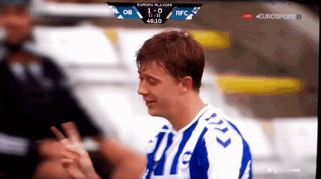 a man in a blue and white striped shirt stands in front of a scoreboard that says europa playoff
