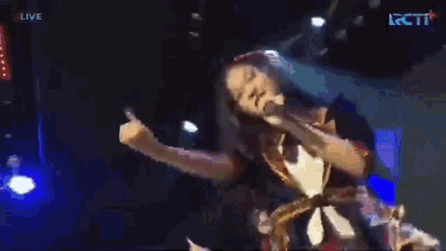a woman is singing into a microphone on a stage with the word live on the bottom right