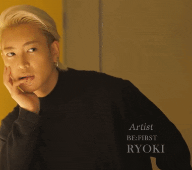 a man wearing a black sweater with the artist be first ryoki written on it