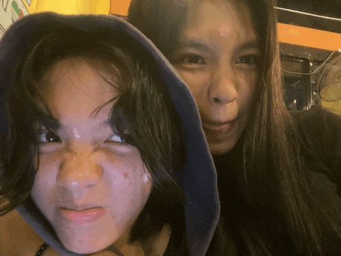 two girls are posing for a picture with one wearing a hood
