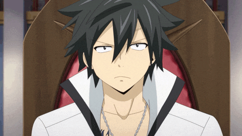 a man with black hair is sitting in a chair and making a funny face