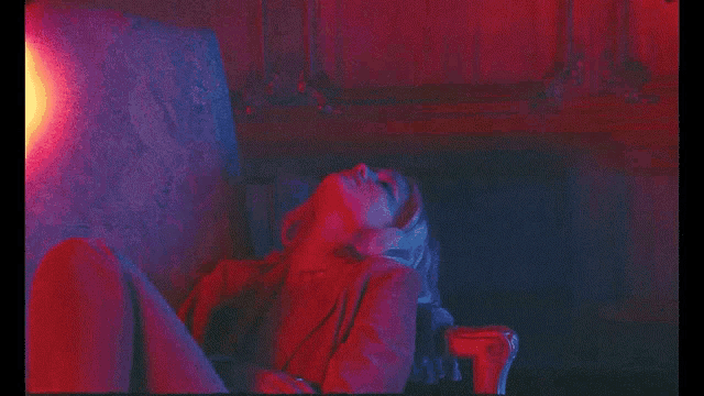 a woman in a red and blue light looks up at the sky