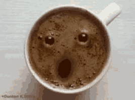 a cup of coffee with a surprised face made out of the foam .