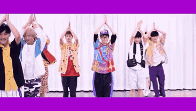a group of young men are standing in a row with their hands in the air