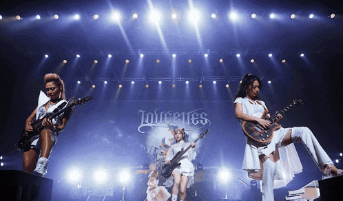 three women playing guitars on a stage with a sign that says infestes