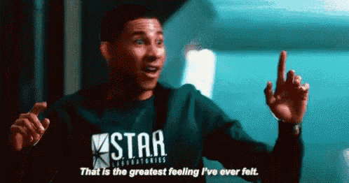 a man is wearing a star labs sweatshirt and pointing up .