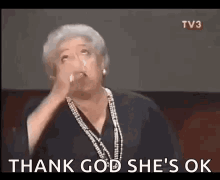 a woman is holding her hand to her face and saying `` thank god she 's ok '' .