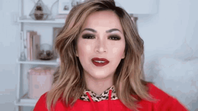 a woman wearing a red sweater and leopard print collar is looking at the camera .