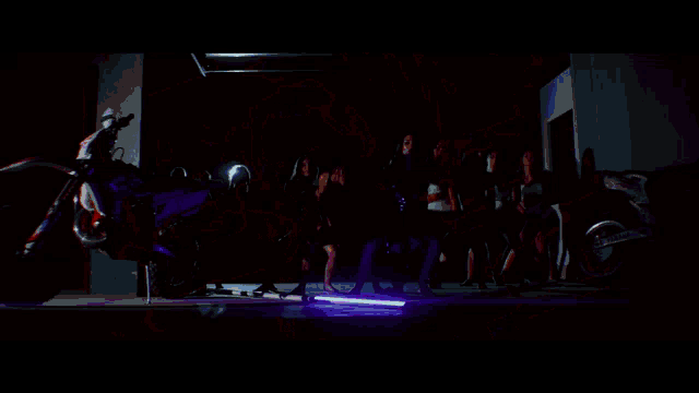 a woman in a red off the shoulder dress is standing in a dark room with purple lights .