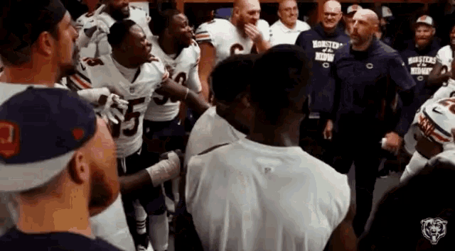 a group of football players are standing in a huddle with their coaches .