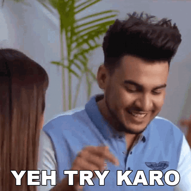 a man in a blue shirt is laughing and says yeh try karo
