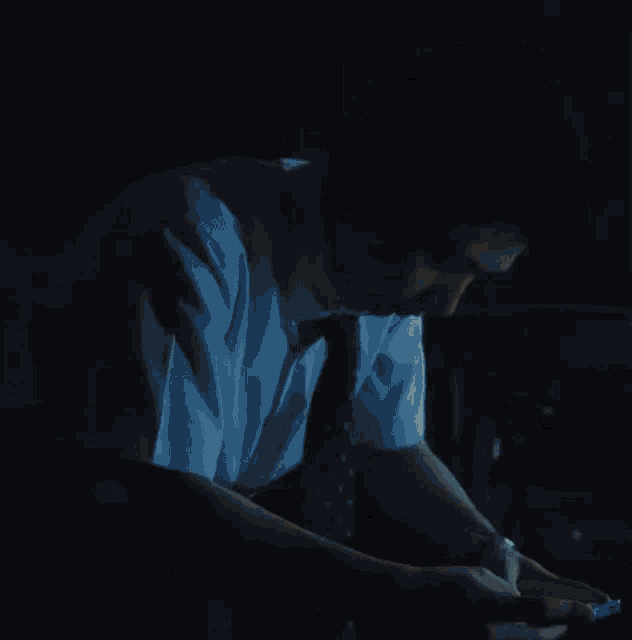 a man in a blue shirt and tie is sitting down