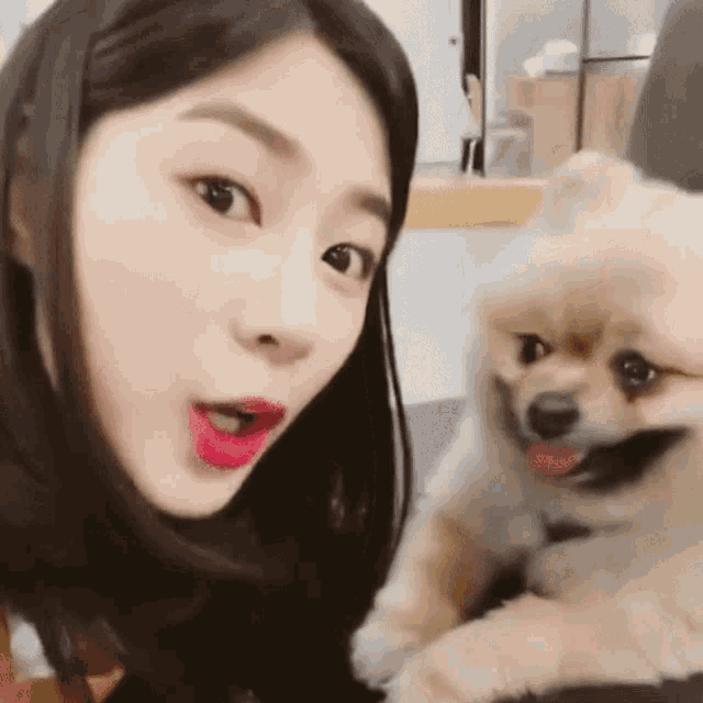a woman is holding a small brown dog and making a funny face
