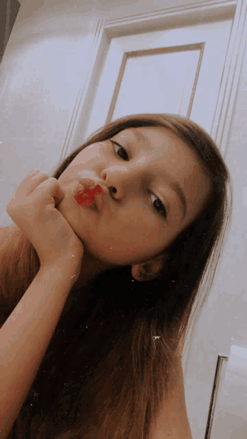 a girl with a gummy bear in her mouth looks at the camera