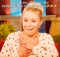 a woman is smiling with her hands on her chest .