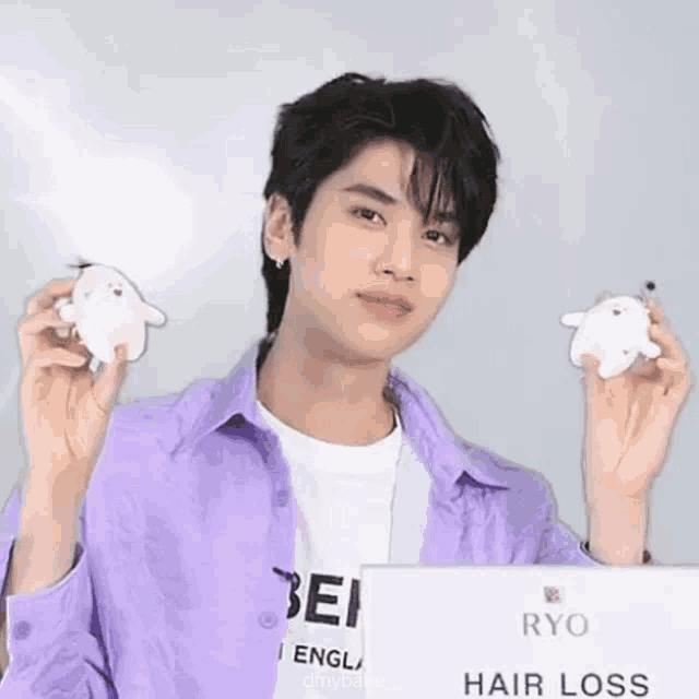a man in a purple shirt is holding a stuffed animal and a sign that says hair loss