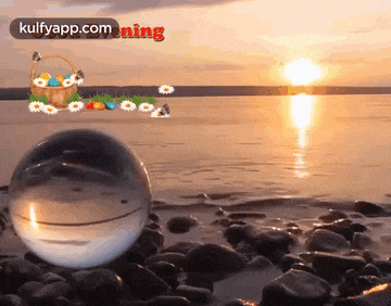 a glass ball is sitting on a rocky beach near a basket of easter eggs ..