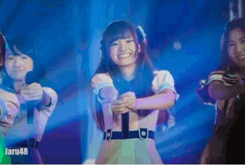 a girl is smiling while holding a microphone with the number 48 on the bottom right