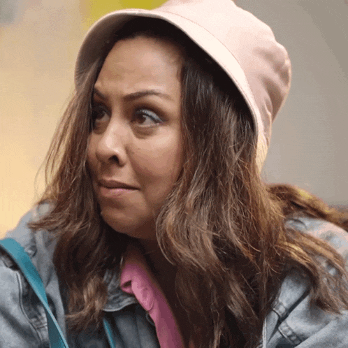 a woman wearing a denim jacket and a pink hat