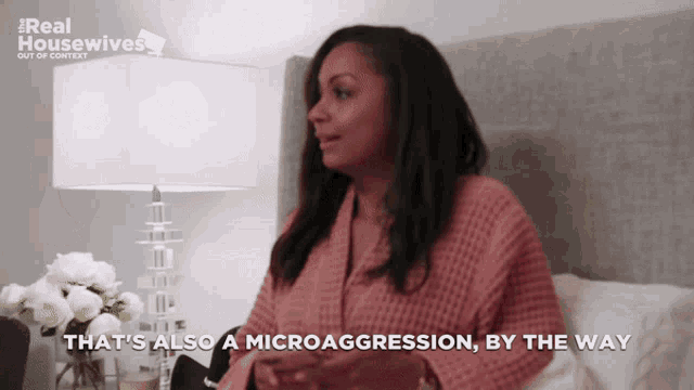 a woman is sitting on a bed with the words that 's also a microagression by the way