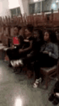 a group of people are sitting in chairs in a room with a lot of empty chairs .