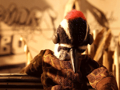 a stuffed bird wearing headphones is standing in front of a sign that says " blocks "