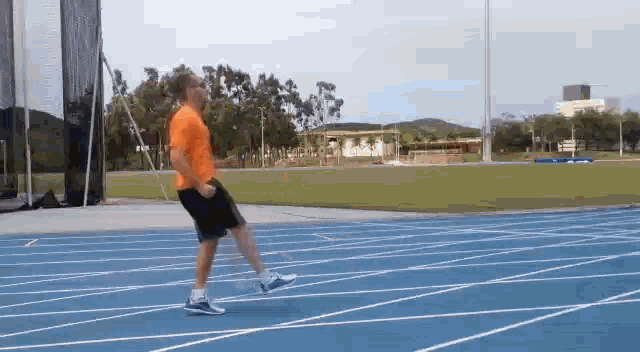 a man in an orange shirt is running on a track .