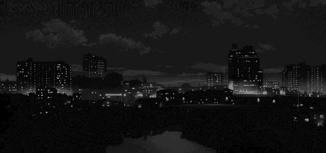 a black and white photo of a city with a river in the foreground