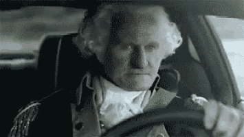 a man in a costume is driving a car .