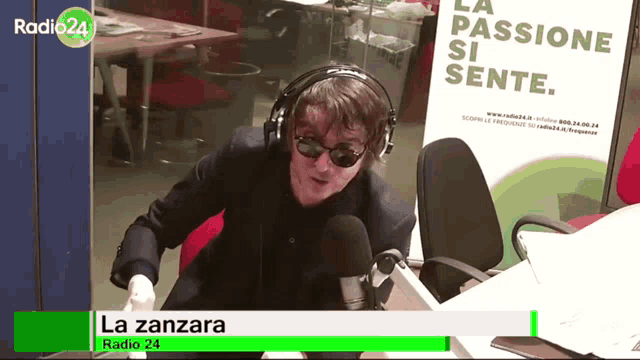 a man wearing headphones and sunglasses is sitting in front of a microphone at radio24