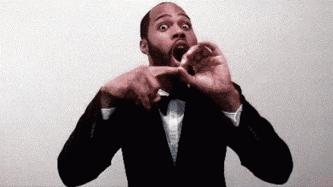 a man in a suit and bow tie is making a funny face with his mouth open .