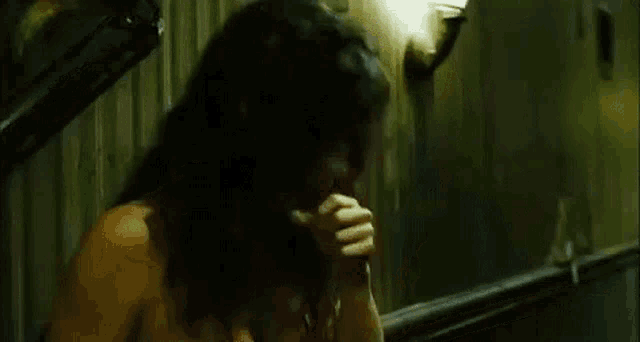 a woman without a shirt is standing in a dark room talking on a phone .