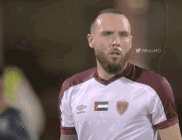 a man with a beard is wearing a white and maroon jersey