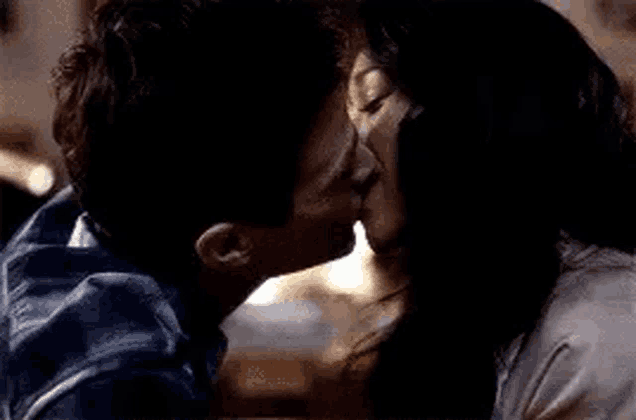 a man and a woman are kissing in front of a dark background .