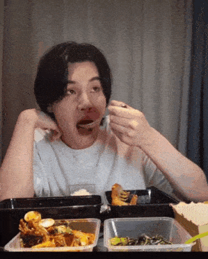 a man is eating food from a plastic container with a spoon in his mouth