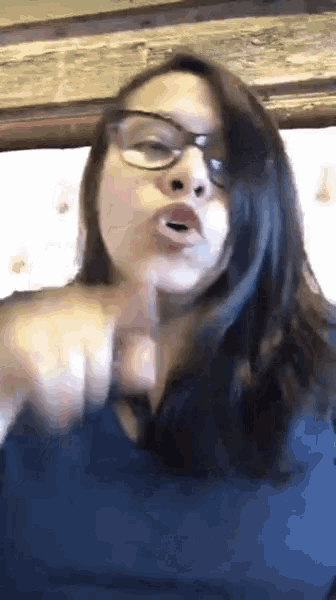 a woman wearing glasses and a blue shirt is pointing
