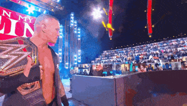 a man is holding a wrestling belt in front of a sign that says n my lin