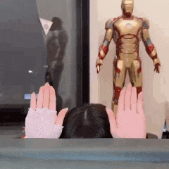 a statue of iron man is behind a woman 's hands