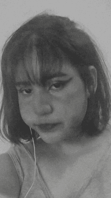 a black and white photo of a girl wearing headphones and making a sad face .